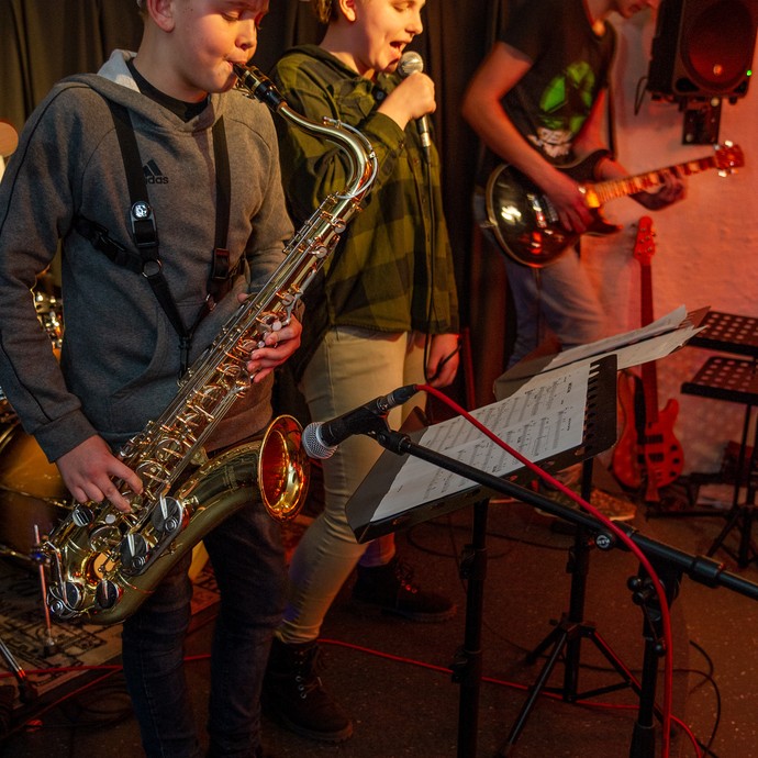 Drei Jugendliche stehen auf einer Bühne und machen Musik. Sie sind aus der Musikschule Greven-Emsdetten-Saerbeck. (vergrößerte Bildansicht wird geöffnet)